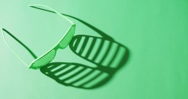 Video of st patrick's green glasses with copy space on green background. St patrick's day, irish tradition and celebration concept.