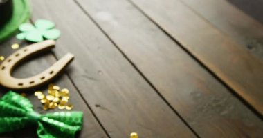 Video of st patrick's green hat, shamrock and horseshoe with copy space on wooden background. St patrick's day, irish tradition and celebration concept.