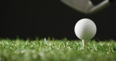 Close up of golf club and ball on grass and black background, copy space, slow motion. Golf, sport and hobby concept.