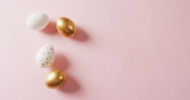 Close up of white and gold easter eggs on pink background with copy space. Easter, tradition and celebration concept.