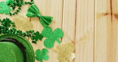 Video of st patrick's green hat, shamrock and bow tie on wooden background. St patrick's day, irish tradition and celebration concept.