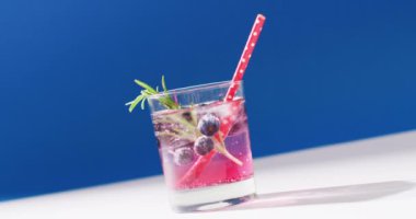 Close up of transparent drink with bluberries on blue background. Cocktail day, party and celebration concept.