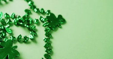 Video of st patrick's green shamrock and necklace on green background. St patrick's day, irish tradition and celebration concept.