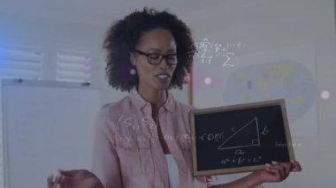 Animation of mathematical equations over african american female teacher holding blackboard. Global education, learning and digital interface concept digitally generated video.