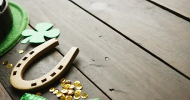 Video of st patrick's green hat, shamrock and horseshoe with copy space on wooden background. St patrick's day, irish tradition and celebration concept.