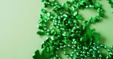 Video of st patrick's green shamrock and necklace on green background. St patrick's day, irish tradition and celebration concept.