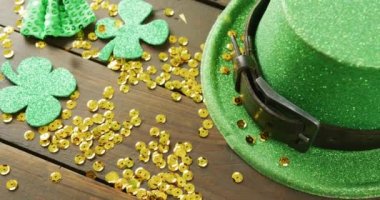 Video of st patrick's green hat, shamrock and gold sequins on wooden background. St patrick's day, irish tradition and celebration concept.