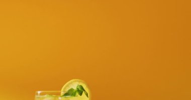 Close up of drink with lemon on yellow background. Cocktail day, party and celebration concept.