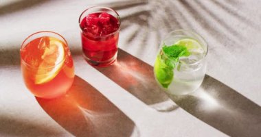 Close up of drinks with orange, raspberry and lemon over shadow. Cocktail day, party and celebration concept.