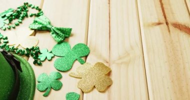 Video of st patrick's green hat, shamrock and bow tie on wooden background. St patrick's day, irish tradition and celebration concept.