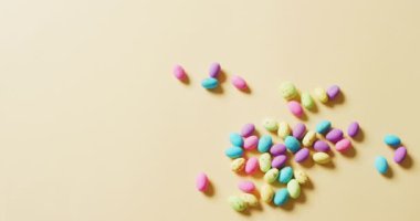 Multiple colorful easter eggs on yellow background with copy space. Easter, tradition and celebration concept.