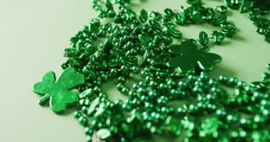 Video of st patrick's green shamrock and necklace on green background. St patrick's day, irish tradition and celebration concept.