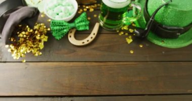 Video of st patrick's glass of beer, hat horse shoe with copy space on wooden background. St patrick's day, irish tradition and celebration concept.