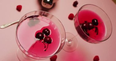 Close up of drinks with cherries and shaker on white background. Cocktail day, party and celebration concept.