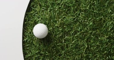 Close up of golf ball on grass with white background, copy space, slow motion. Golf, sport and hobby concept.