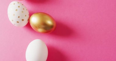 Close up of white and gold easter eggs on pink background with copy space. Easter, tradition and celebration concept.