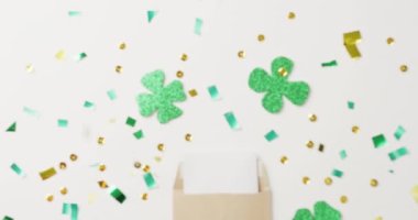 Video of st patrick's green shamrock, letter and sequins on white background. St patrick's day, irish tradition and celebration concept.