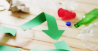 Close up of trash and recycling symbol of green paper arrows on wooden background. Global recycling, ecology and nature concept.