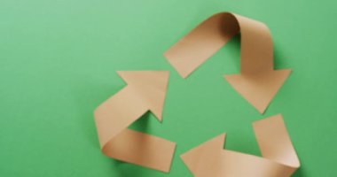Close up of recycling symbol of paper arrows on green background, with copy space. Global recycling, ecology and nature concept.