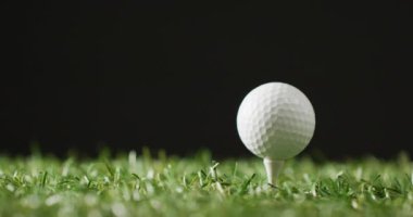 Close up of golf club and ball on grass and black background, copy space, slow motion. Golf, sport and hobby concept.