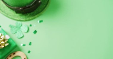 Video of st patrick's green shamrock leaf and hat with copy space on green background. St patrick's day, irish tradition and celebration concept.