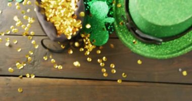 Video of st patrick's green hat, shamrock and gold sequins on wooden background. St patrick's day, irish tradition and celebration concept.