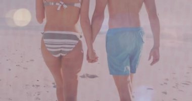 Animation of lens flares and rear view of caucasian couple holding hands and walking at beach. Digital composite, love, togetherness, trunks, panties, midsection, vacations, sunlight, enjoyment.
