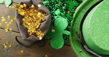 Video of st patrick's green hat, shamrock and gold sequins on wooden background. St patrick's day, irish tradition and celebration concept.