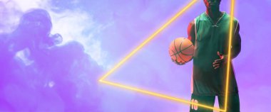 Midsection of african american male player with basketball by glowing triangle on smoky background. Copy space, composite, illuminated, sport, competition, illustration, shape and abstract concept.