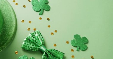 Video of saint patricks day green shamrock, hat and bow tie with copy space on green background. Saint patricks day, irish tradition and celebration concept.