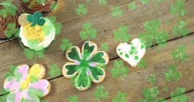 Animation of st patrick's day shamrock and cupcakes on wooden background. St patrick's day, irish tradition and celebration concept digitally generated video.