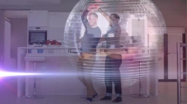 Animation of disco ball and light trails over diverse male couple dancing in kitchen. Art, hobby and music concept digitally generated video