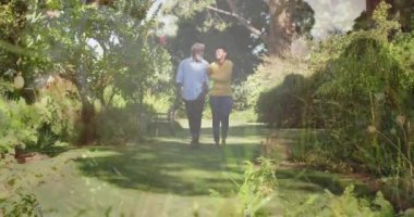 Animation of grass over african american couple walking in garden. Gardening, lifestyle and nature concept digitally generated video.