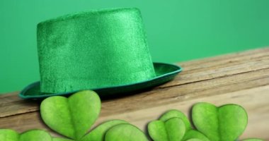 Animation of st patrick's day shamrock and green hat on green background. St patrick's day, irish tradition and celebration concept digitally generated video.