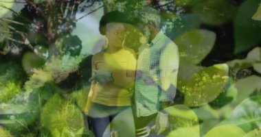 Animation of leaves over african american couple working in garden. Gardening, lifestyle and nature concept digitally generated video.