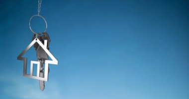 Animation of silver key with house keychain on blue background. Abstract background, pattern and movement concept, digitally generated video.