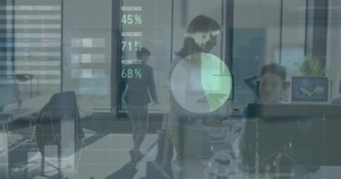 Caucasian and mixed race businesswomen working in a modern office, discussing, holding digital tablet and looking at computer screen, their colleagues working in the background, slow motion.  