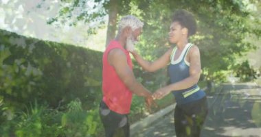 Animation of trees over african american couple stretching, slow motion. Sport, fitness and healthcare concept digitally generated video.