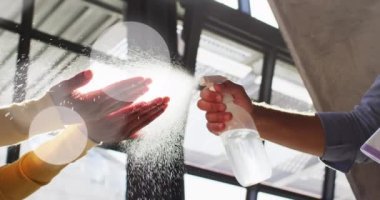 Animation of light spots over diverse people disinfecting hands. Protection, virus, healthcare and lifestyle concept digitally generated video.