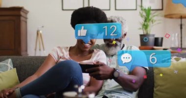 Animation of social media icons and networks over african american man and woman with tablet. Global social media, networks, computing and data processing concept digitally generated video.