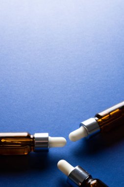 Image of three bottles with pumps and copy space on blue background. Plastic free beauty, health and beauty, sustainability concept.