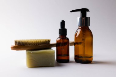 Image of glass bottles with pumps, soap, brush and copy space on white background. Plastic free beauty, health and beauty, sustainability concept.