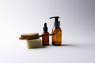 Image of glass bottles with pumps, soap, brush and copy space on white background. Plastic free beauty, health and beauty, sustainability concept.