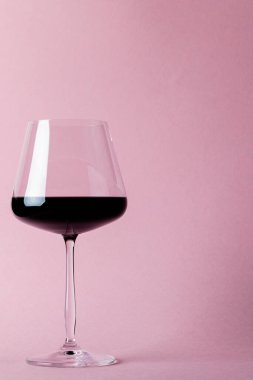 Glass of red wine on pink background, with copy space. Wine week, drink and celebration concept.