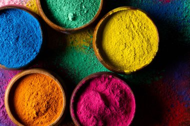 Close up of multi coloured powder in bowls and copy space on black background. Holi festival, colour, hindu tradition and celebration concept.