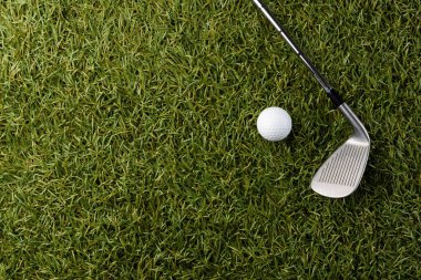 High angle view of white golf ball and golf club on grass with copy space. Golf, sports and competition concept.