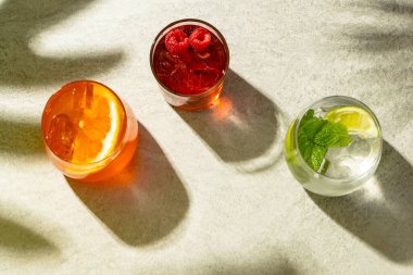 Glasses with diverse cocktails with drinks over beige background with shadows. Drinks, cocktails, beverages and party concept.
