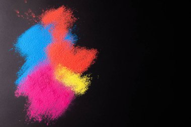 Close up of multi coloured powder and copy space on black background. Holi festival, colour, hindu tradition and celebration concept.