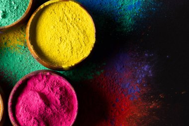 Close up of multi coloured powder in bowls and copy space on black background. Holi festival, colour, hindu tradition and celebration concept.