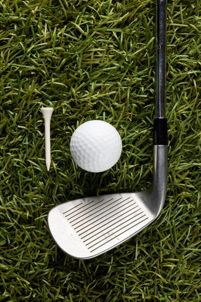 White tee, golf ball and golf club on grass with copy space. Golf, sports and competition concept.